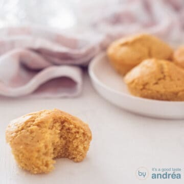 A square photo with a muffin with a bite in it, giving you a light structure. A plate of muffins in the background.