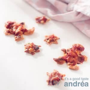 A square photo with a white background with mini pizzas in Christmas shapes and a pink and white tea towel