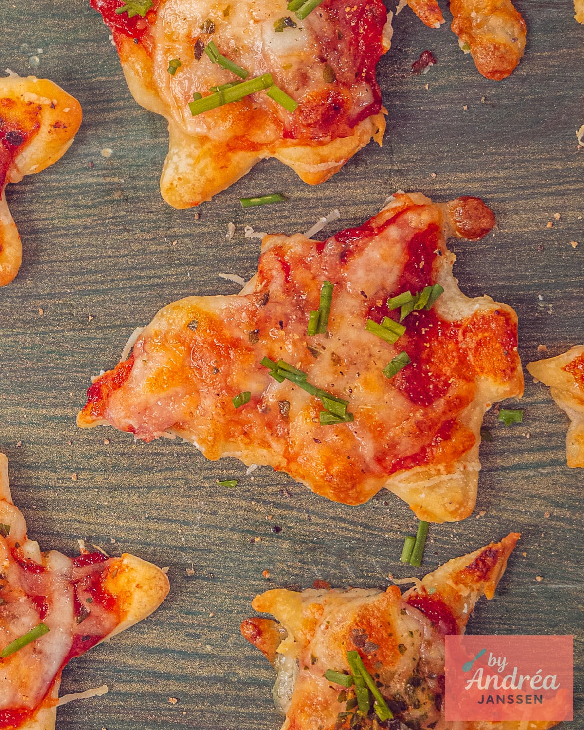 Close-up van gebakken mini kerst pizza's met tomatensaus, gesmolten kaas en verse bieslook op een houten ondergrond