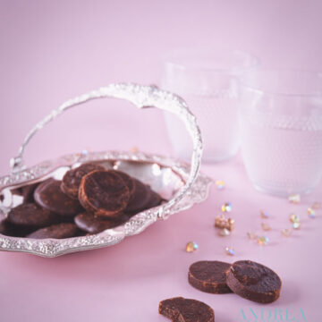 A silver platter with chocolate fondant. Some fondants in the front and all in a pink background