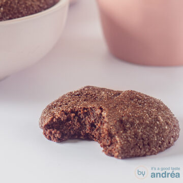 A square photo with a chocolate chip cookie with a bite bitten on it on a white background