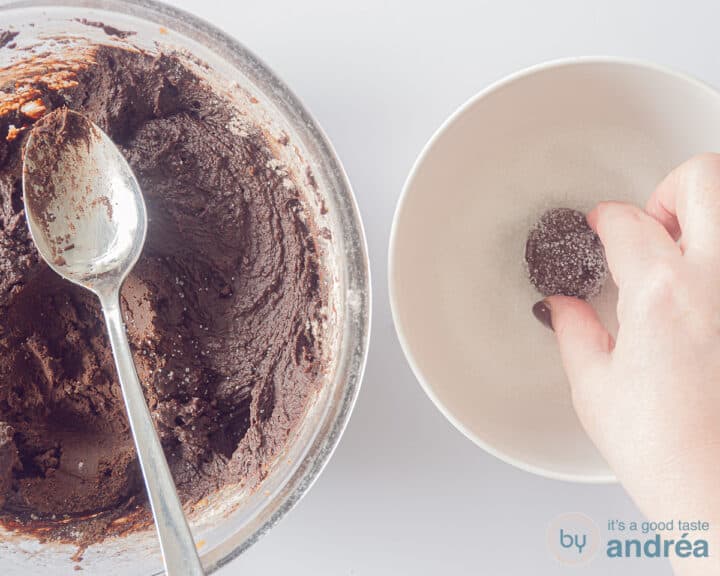 A bowl with chocolate dough and a bowl with fine sugar through which a ball of chocolate dough is rolled