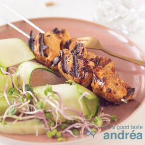 two chicken skewers and a cucumber salad