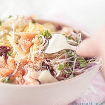 a white plate with spaghetti with smoked salmon and sun-dried tomatoes
