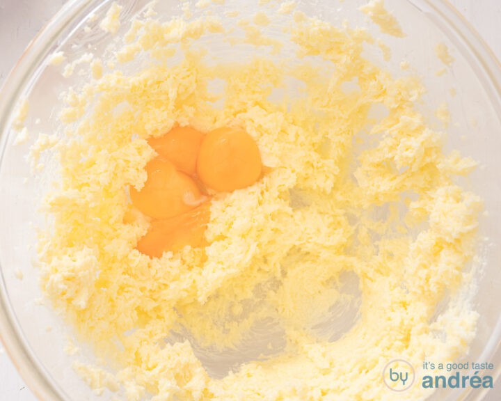 The eggs are added to the butter-sugar mixture in the glass bowl.