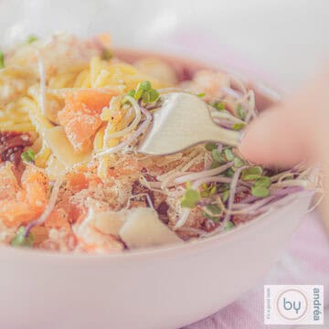 A square photo with spaghetti, smoked salmon and Parmesan cheese. A fork pokes it.