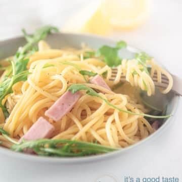 a white bowl with spaghetti, arugula and capers