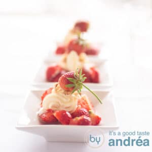A square photo with three white bowls filled with strawberries, walnuts and cream cheese. Topped with a strawberry