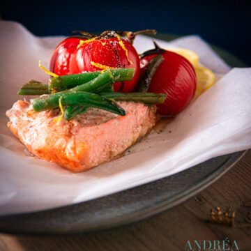 a baking paper with steamed salmon with tomatoes and greens