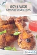 one drumstick in the middle and several on the left next to it. A glass dish with chili sauce on the right. A text overlay: Soy Sauce Chicken Drumsticks, dinner, easy recipe.