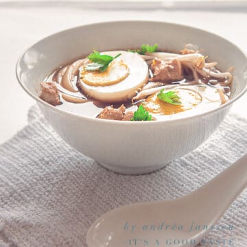 a white bowl filled with Ramen Noodle soup with an egg