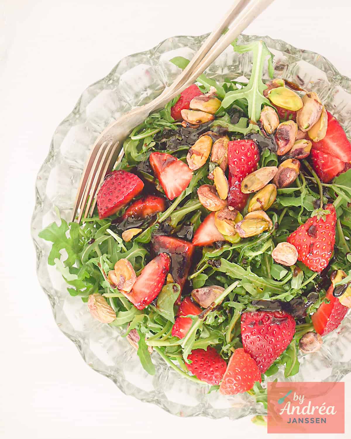 A top-down picture of a salad, strawberry and pistachio.