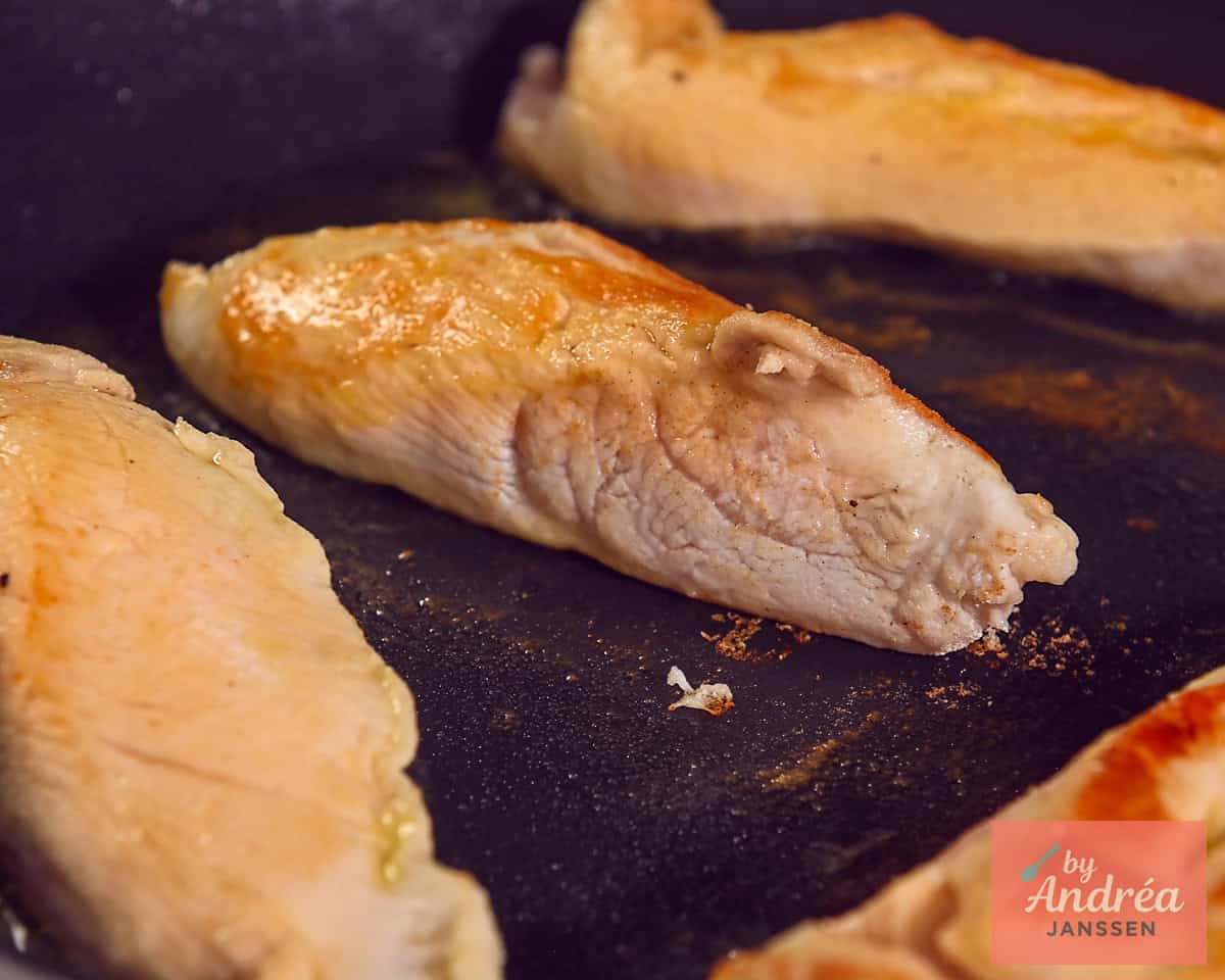 Chicken breasts are seared in a skillet until golden brown on both sides.