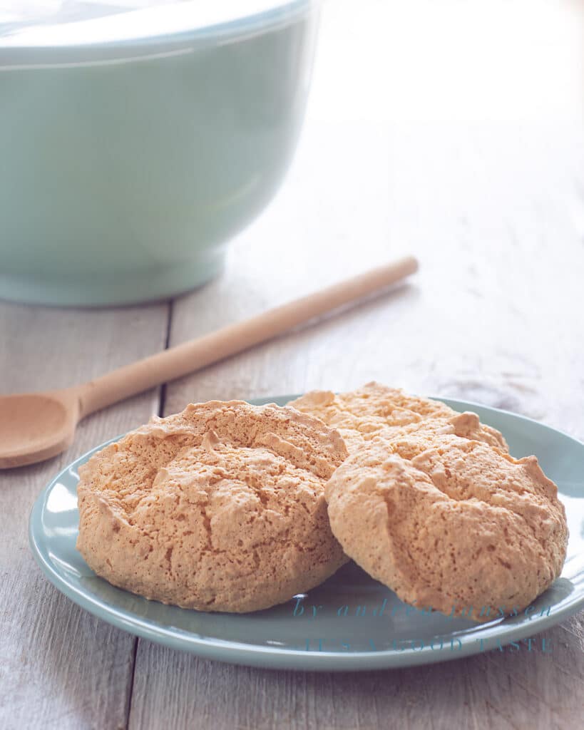Three sponge cookies on a blue plate with a blue bowl in the background