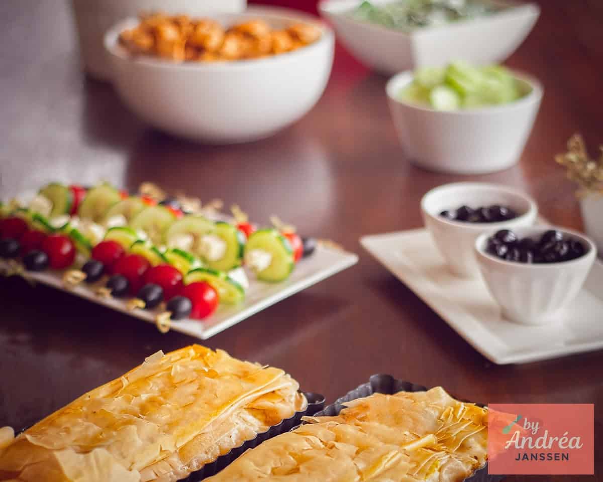 A wide shot of a buffet table with various Greek recipes