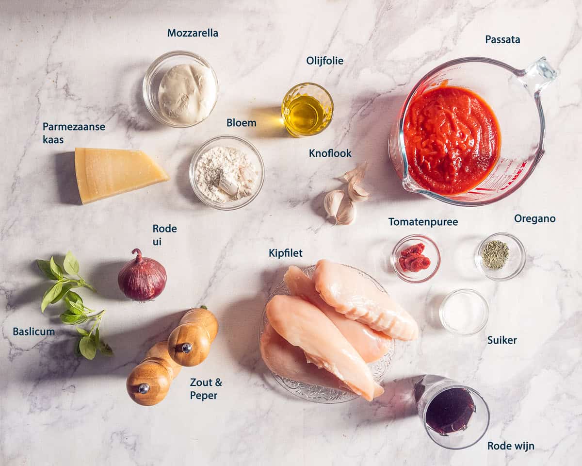Ingrediënten voor kip pizzaiola: kipfilet, passata, mozzarella, Parmezaanse kaas, rode ui, knoflook, tomatenpuree, basilicum, oregano, olijfolie, bloem, suiker, rode wijn, zout en peper.
