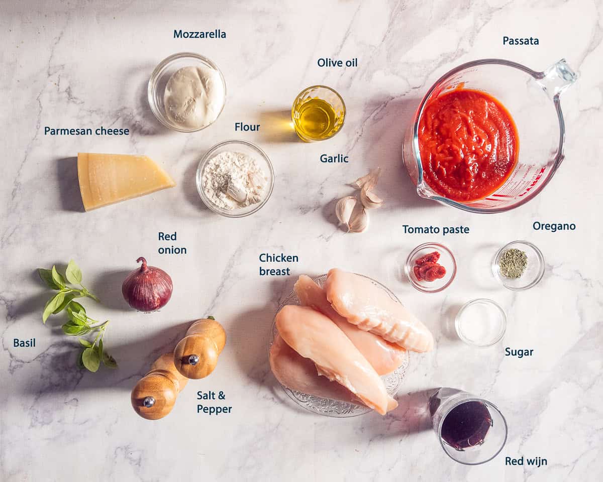 Ingredients for chicken pizzaiola: chicken breast, passata, mozzarella, Parmesan cheese, red onion, garlic, tomato paste, basil, oregano, olive oil, flour, sugar, red wine, salt, and pepper.