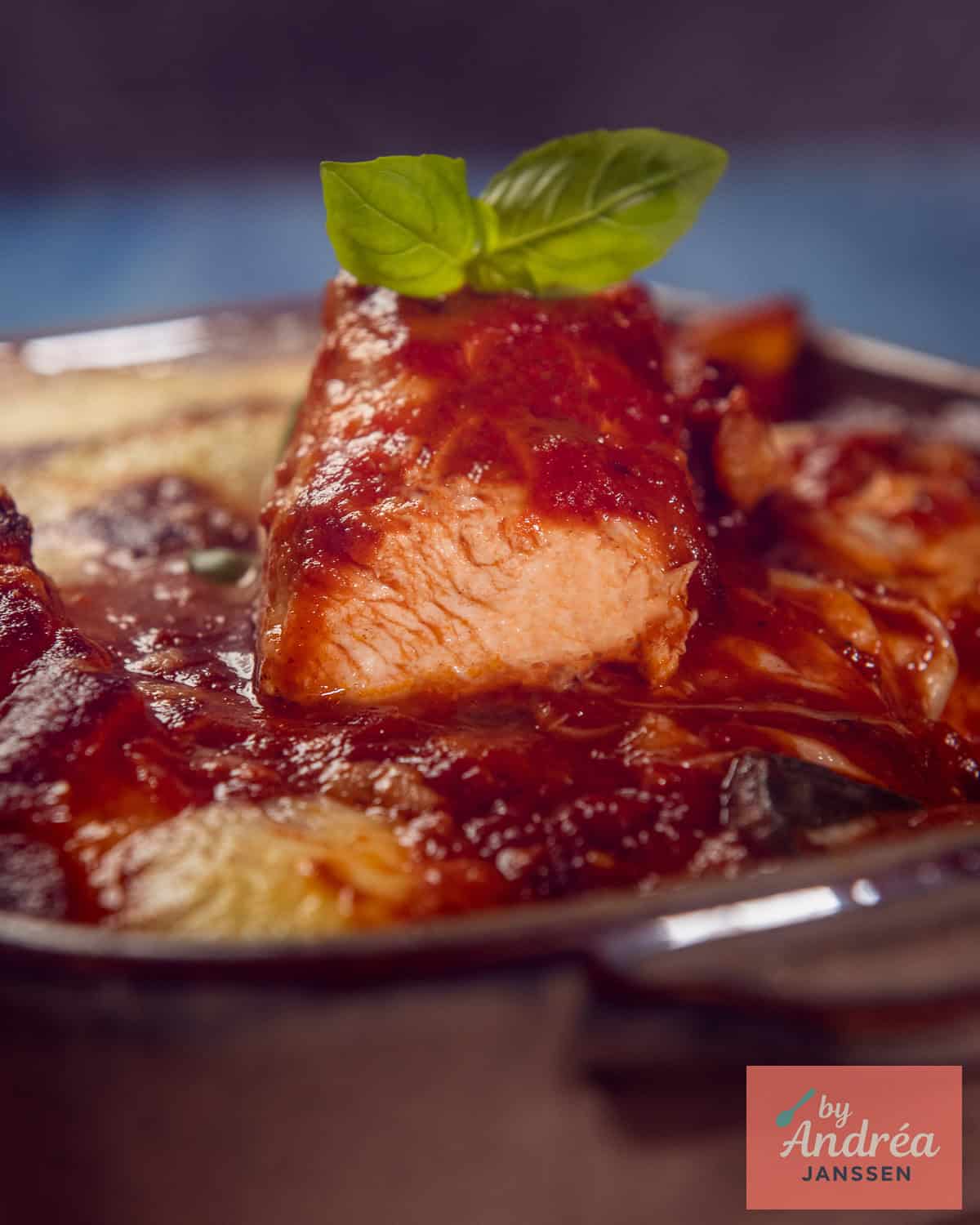Sliced chicken breast in tomato sauce with melted mozzarella and fresh basil.