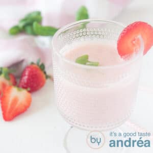 a square photo with a glass filled with a smoothie with strawberries and basil