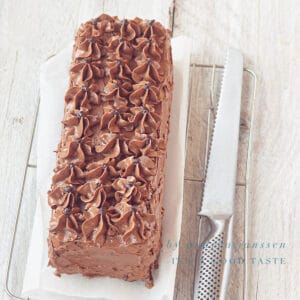 A square photo with a chocolate truffle cake on a rack on a baking paper. Cut off a piece