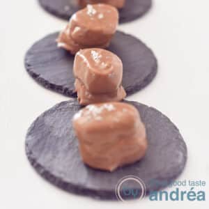 A square photo with three chocolate dipped marshmallows with beer on a slate background on a white background