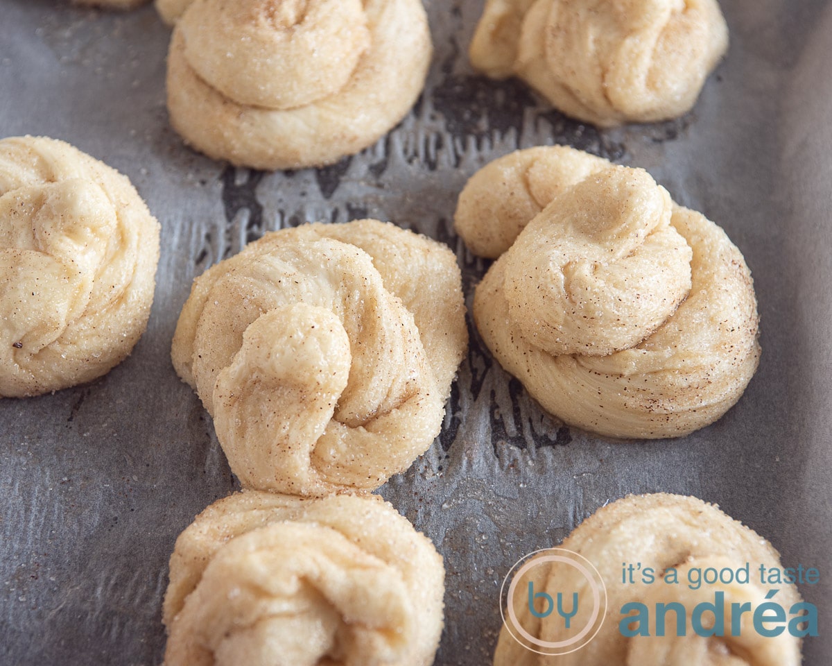 7 round balls of dough twisted into a knot on a baking tray