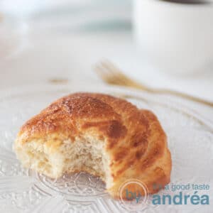 a square photo with a bolus that has been bitten. A fork and a cup in the background