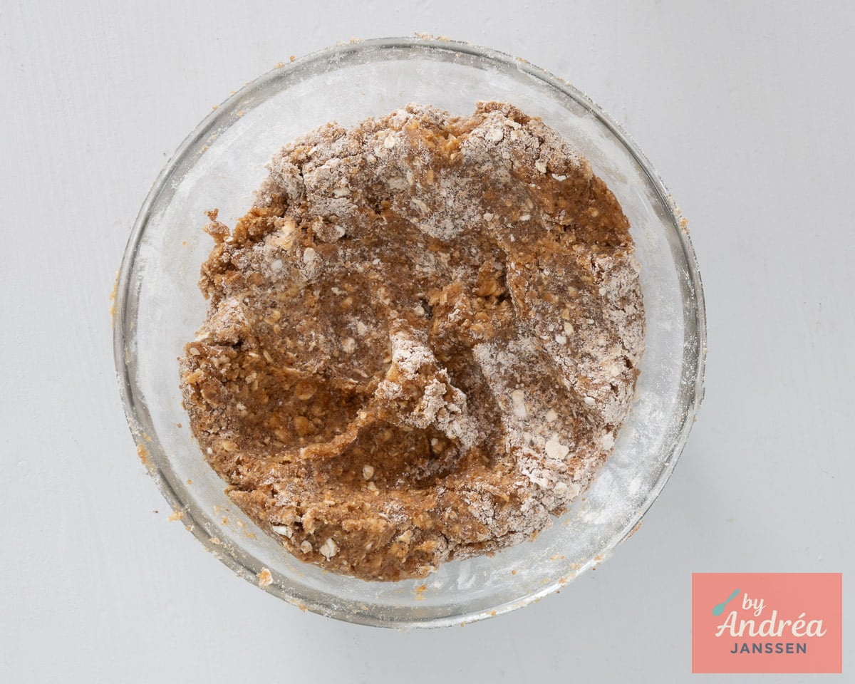 Overhead view of crumble dough with visible oats and flour in a glass mixing bowl.