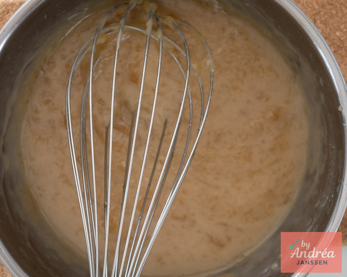 Light brown sauce for the apple filling in a stainless steel saucepan with a whisk.