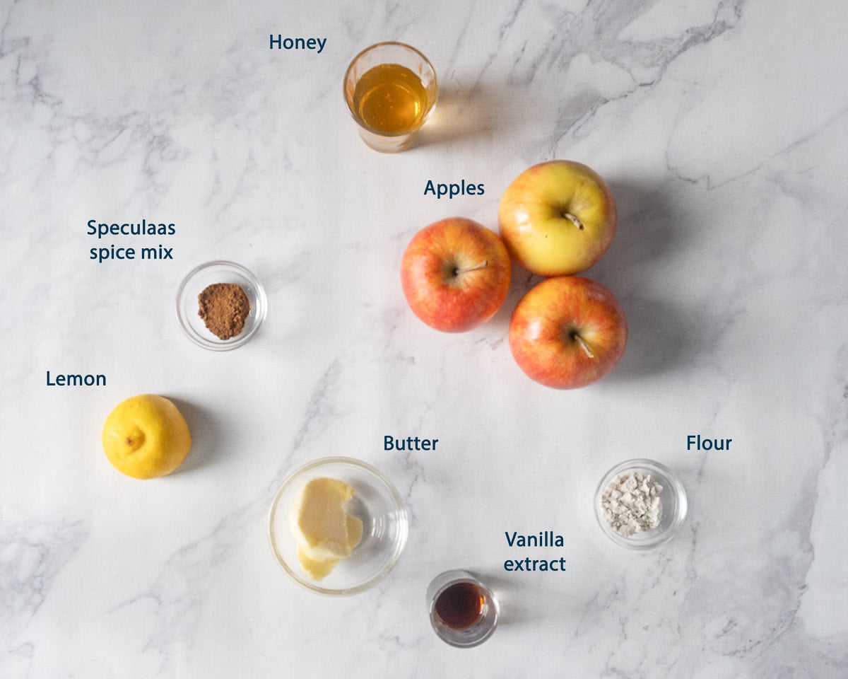 Apples, honey, speculaas spice mix, lemon, butter, flour, and vanilla extract for the apple filling, with English labels.