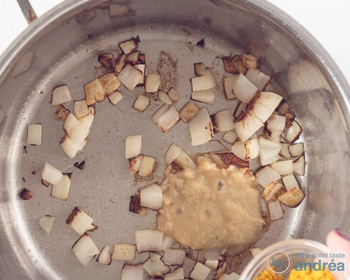 An onion is fried in a pan. Garlic and herbs are added.