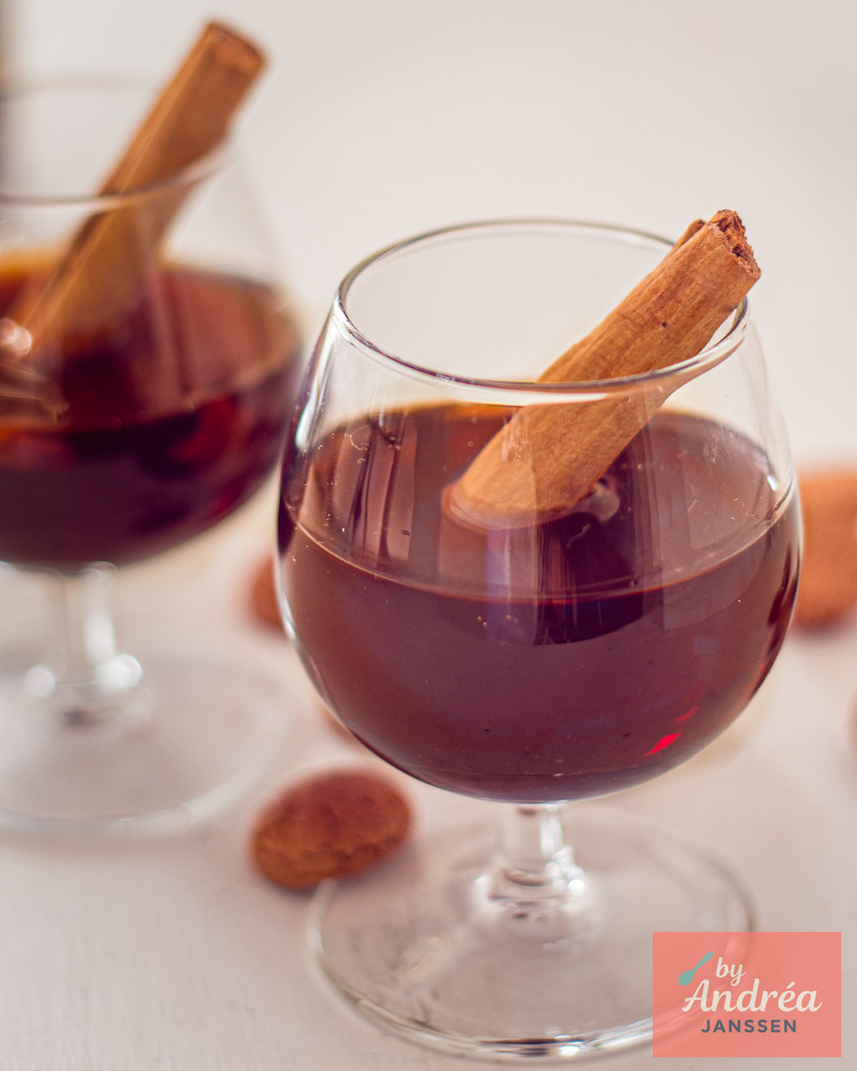 Glass of dark homemade spiced liqueur with a cinnamon stick and spiced cookies