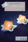 A blue background with white star-shaped trays filled with smoked salmon and arugula oil, wasabi, onion and a piece of toast. A text description of the recipe at the top