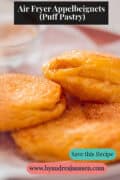 Warm puff pastry apple fritters dusted with sugar on a serving plate a text on top: Air Fryer Appelbeignets (Puff Pastry)