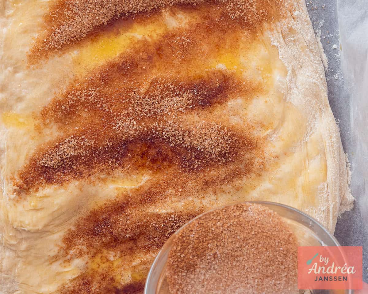 Cinnamon sugar is sprinkled on top of dough