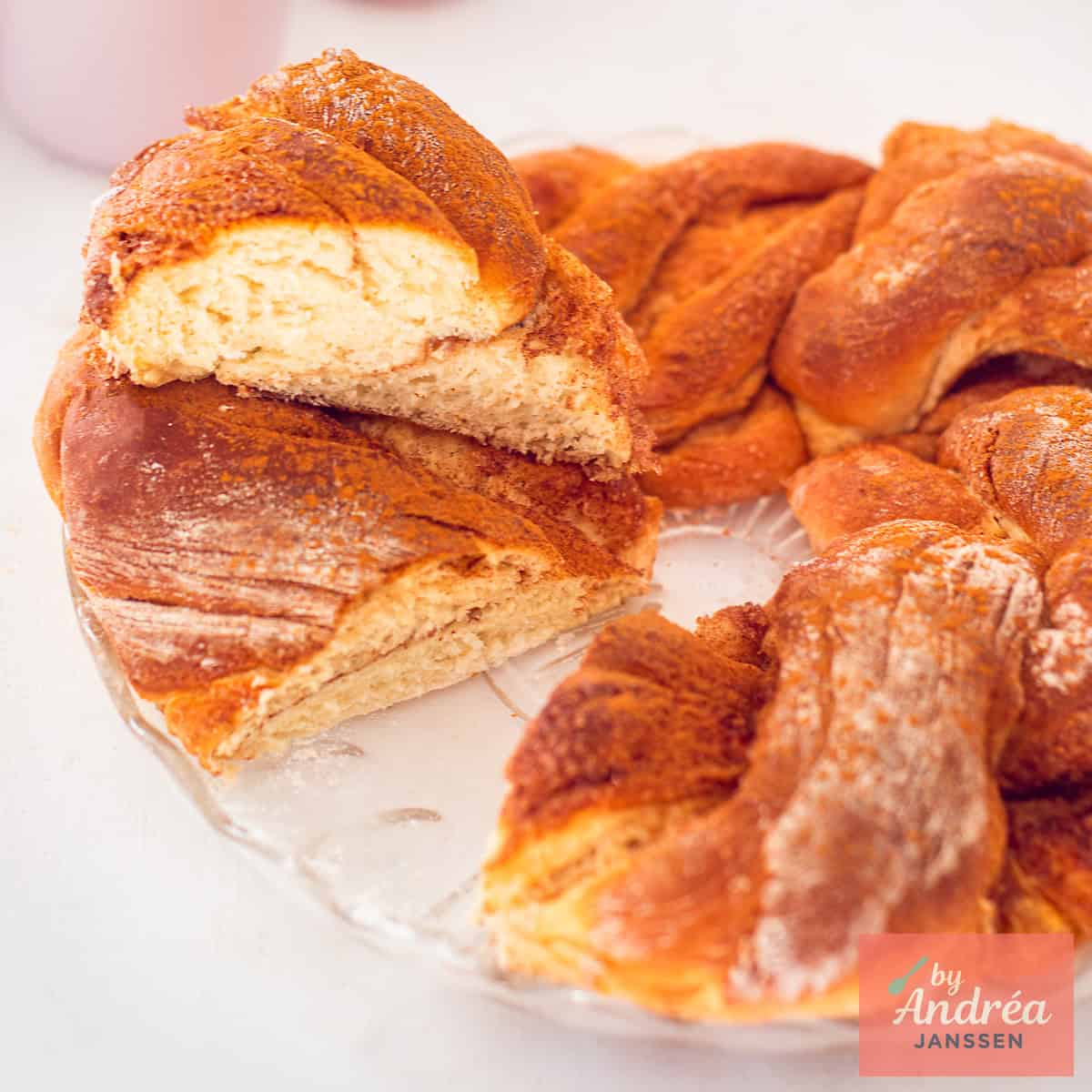 Square picture with part of a cinnamon wreath bread. A slice cut out and placed on top.