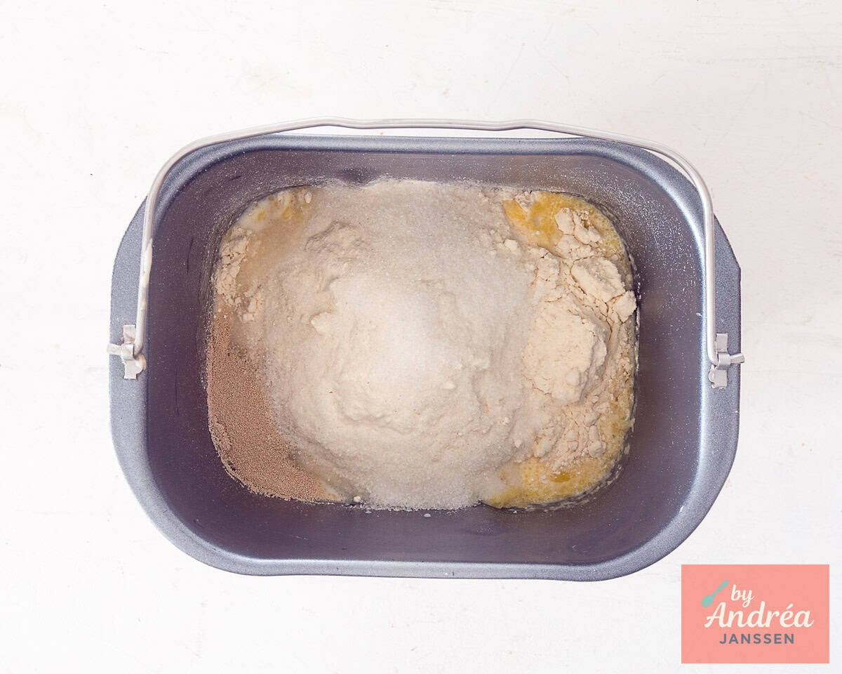 All ingredients for a bread dough in a baking machine pot.