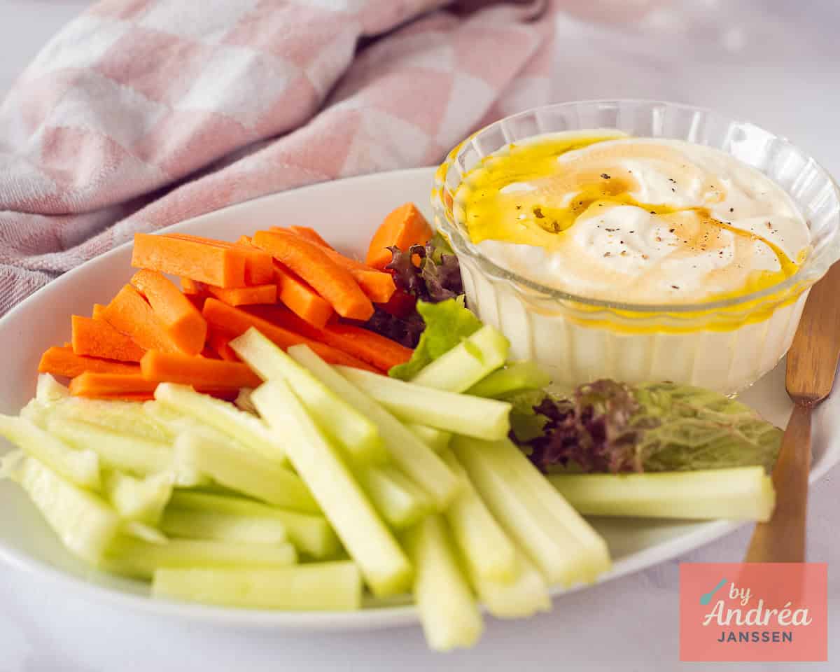 Een breedtefoto met een bord met rauwkost en een romige feta dip.