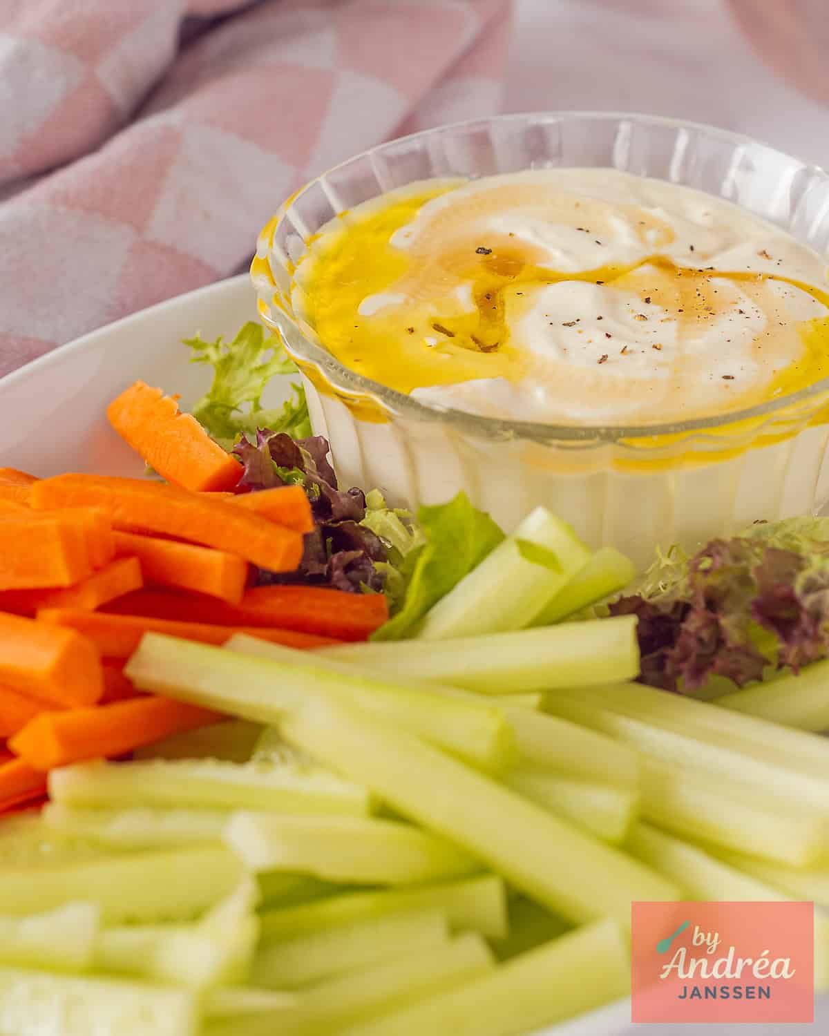 Een foto met een romige dip van feta, yoghurt, crème fraîche en smaakmakers. met rauwkost op een bord.