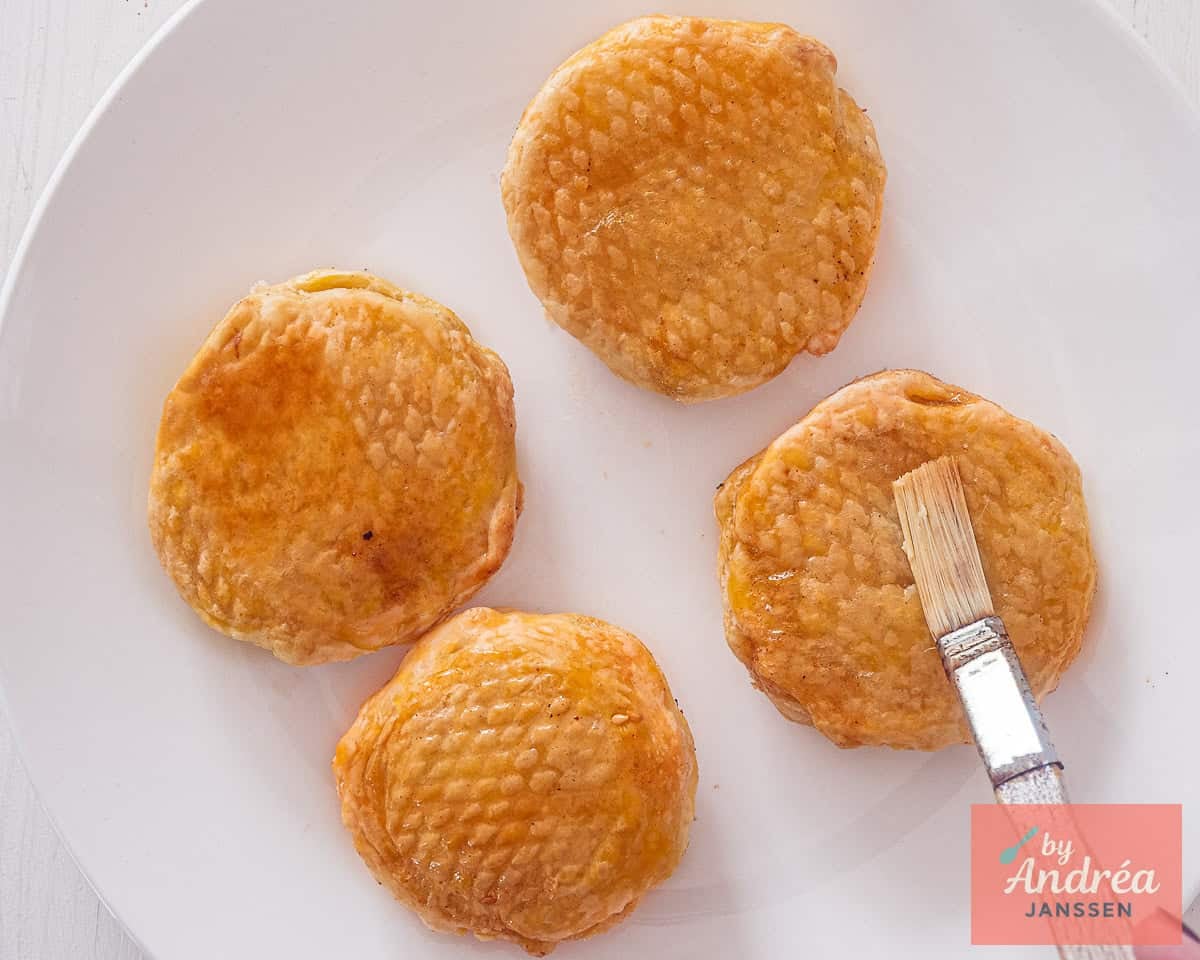 Brushing warm air fryer appelbeignets with melted butter