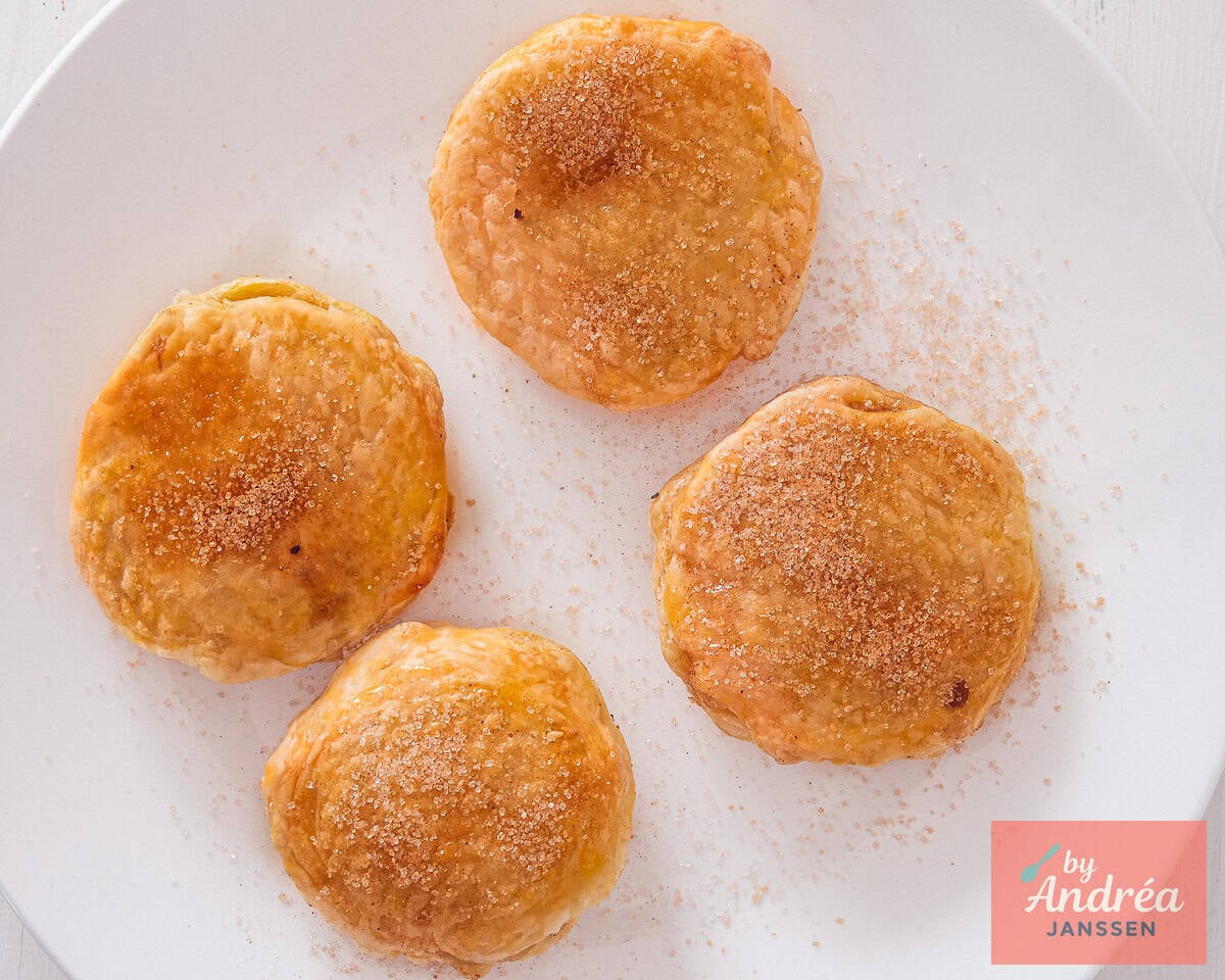 Sprinkling cinnamon sugar over puff pastry appelbeignets after baking