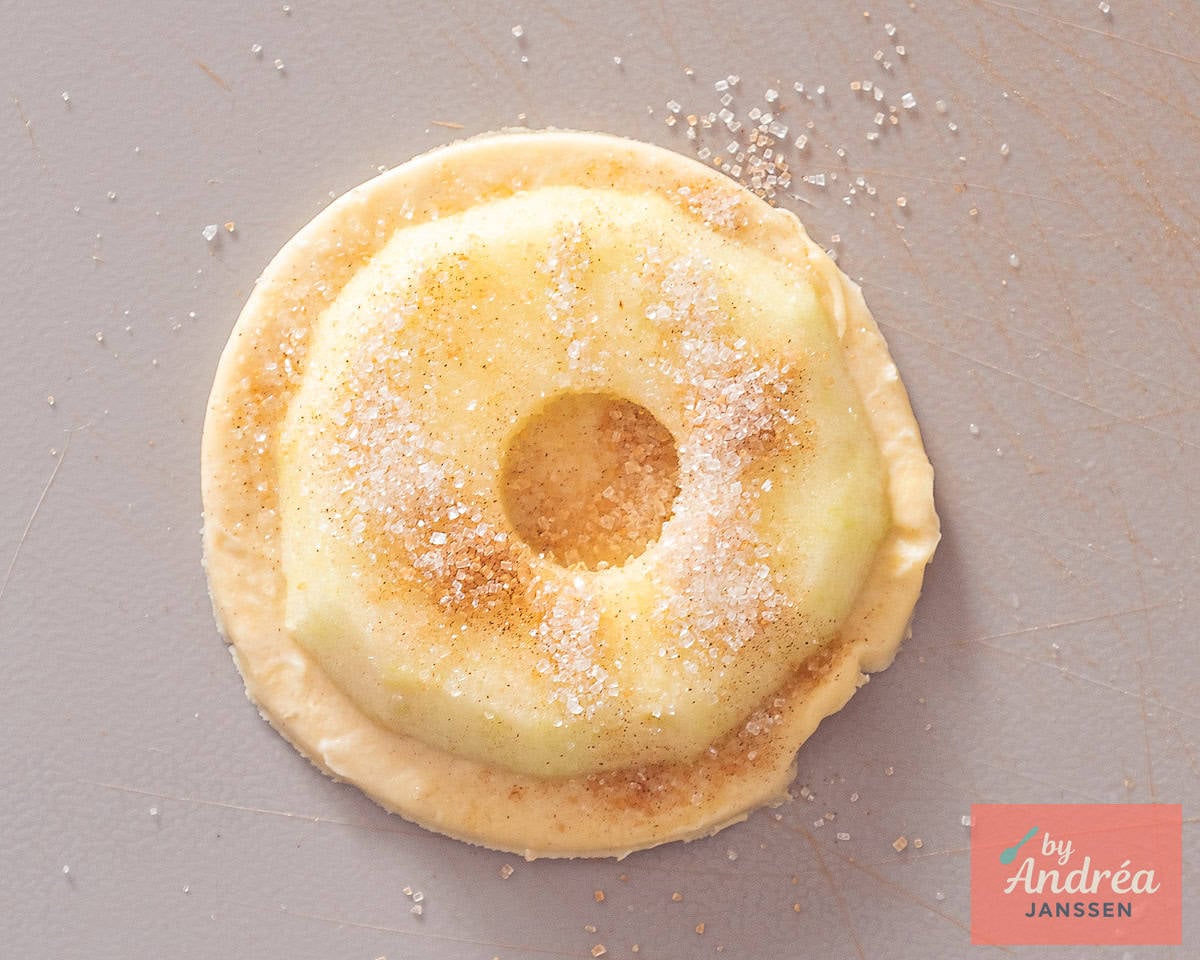 Apple ring placed on puff pastry with cinnamon sugar before sealing
