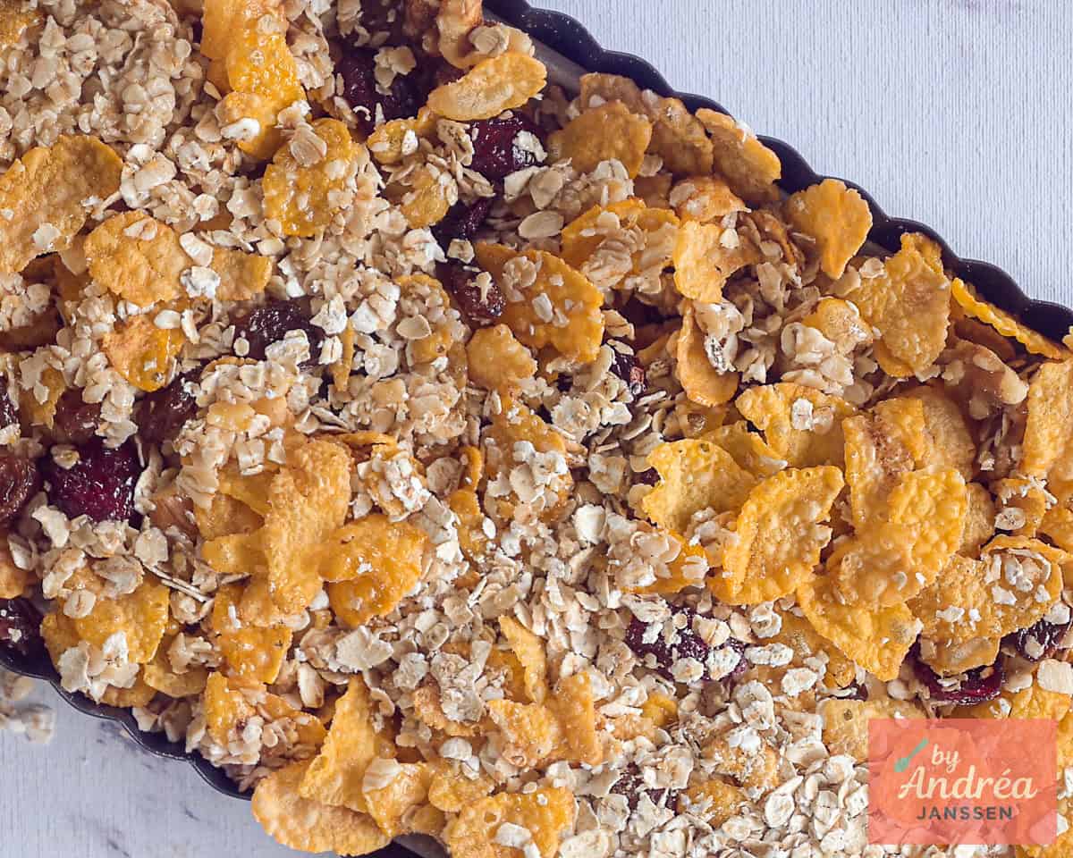 The cornflakes - oats mix with fruits and nuts is placed into a baking tin