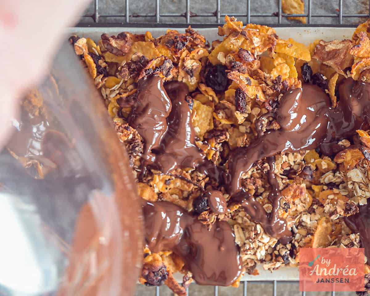 Melted chocolate is poured on top of the granola bars