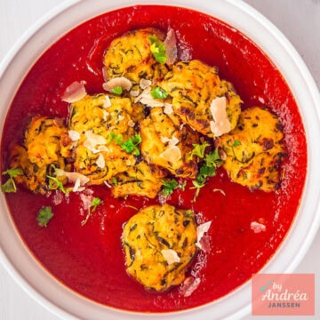 A square photo of a white bowl with tomato sauce and zucchini meatballs, delicious vegetarian.