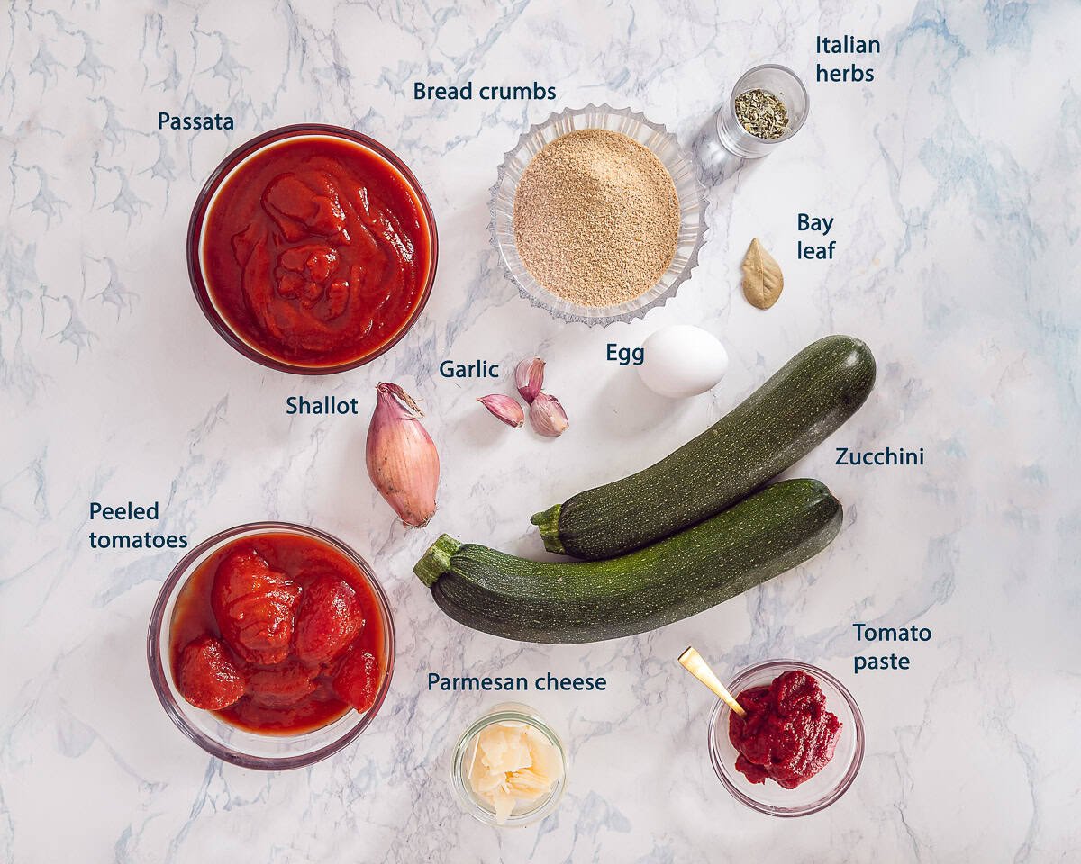 Ingredients Zucchini Meatballs In Tomato Sauce on a white marbled background with text description