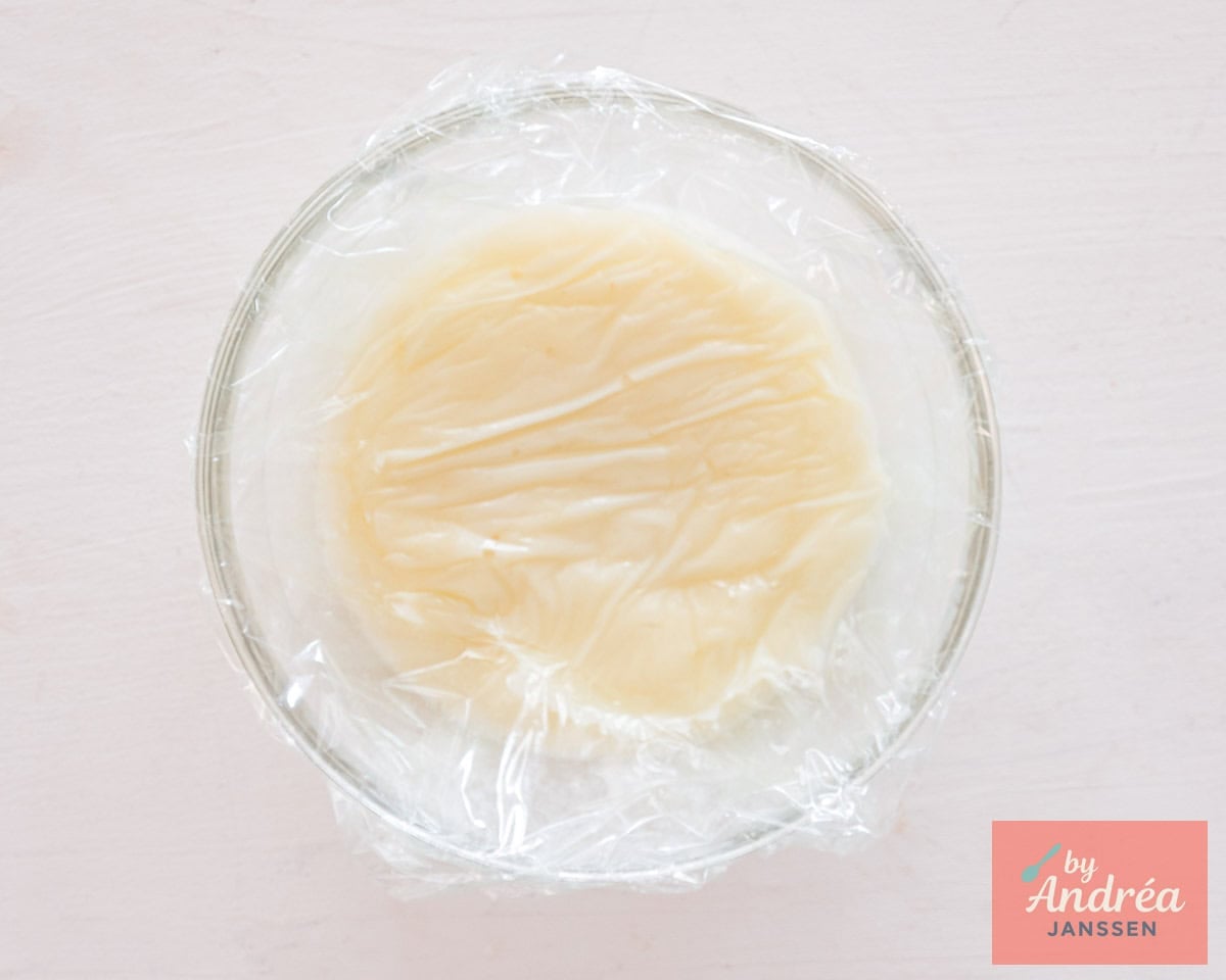 Custard cooling down in a glass bowl covered with plastic foil