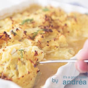 a square photo of a white casserole taking out a cod fillet with Rösti topping