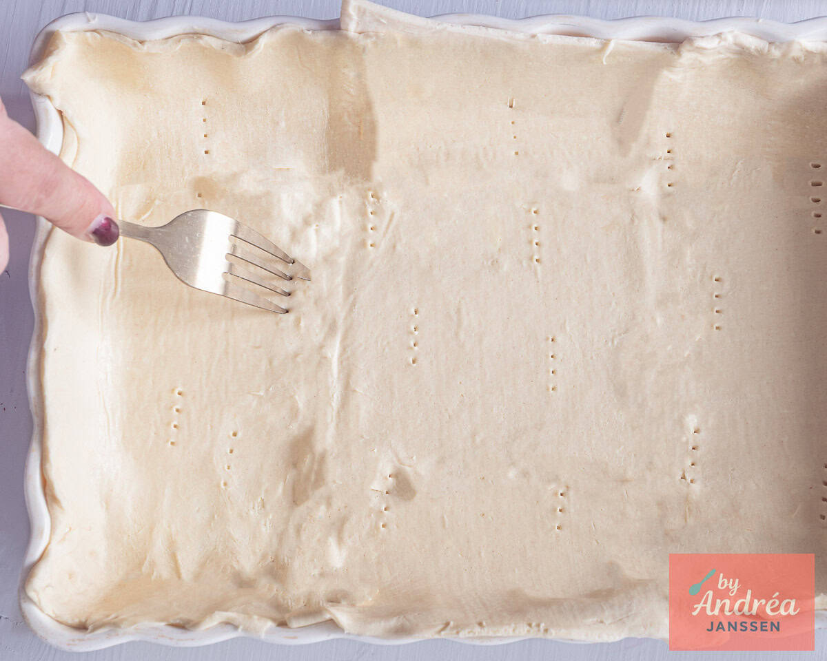 Bedek de ovenschaal met bladerdeeg en prik met een vork gaatjes
