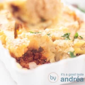 A square photo showing part of a white baking dish filled with spinach, ground beef and mashed potatoes.